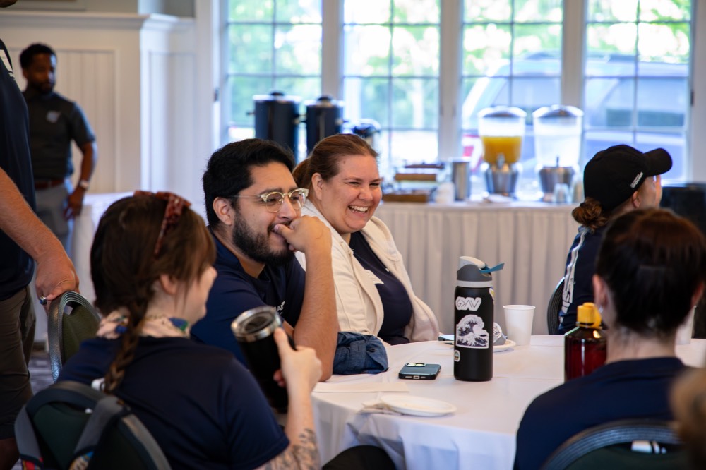 Group of GVSU Alumni smile while they sit at table together